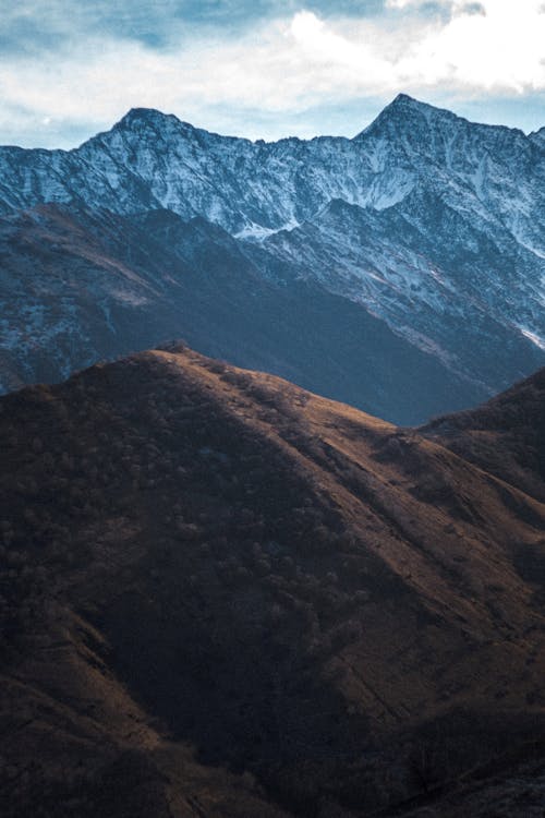 A Brown Mountain Near a Snow Capped Mountain