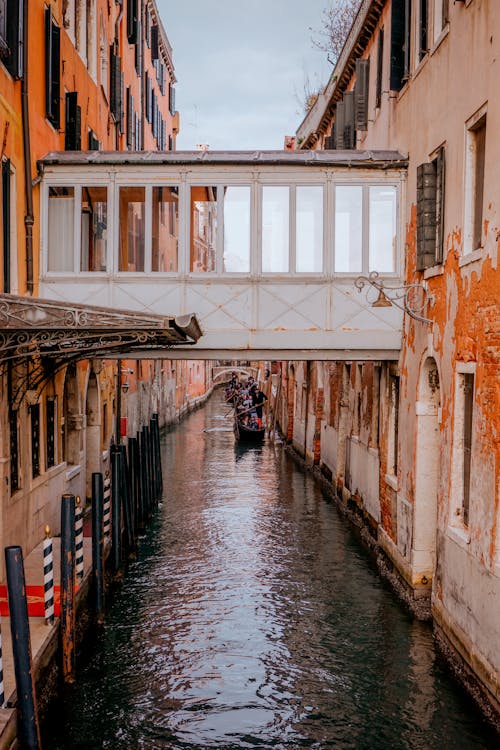 Free People Riding a Gondola on a Narrow canal Between Houses Stock Photo
