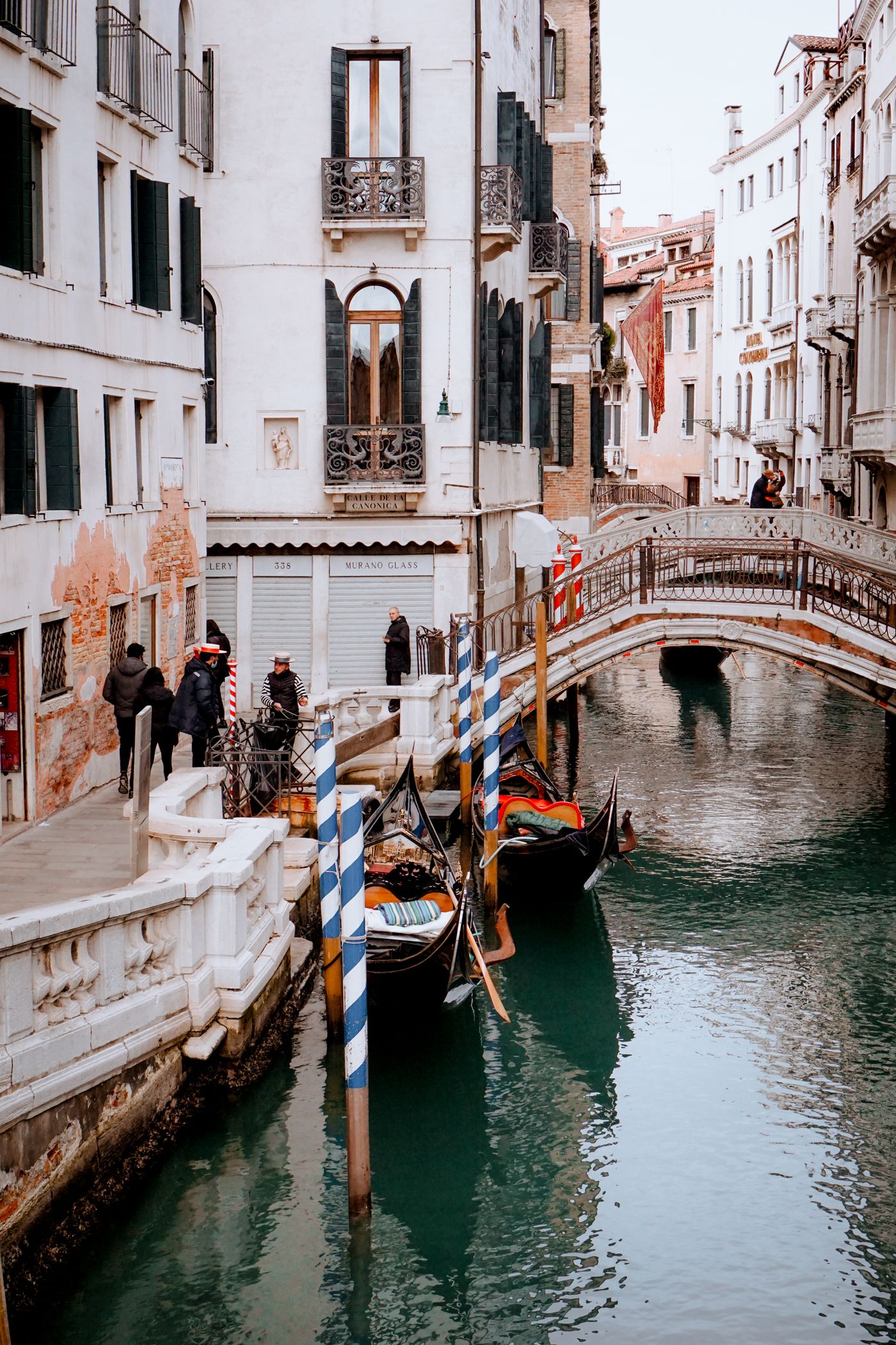 Gondolas moored on a canal in Venice, Italy, with a stone bridge and historic buildings behind