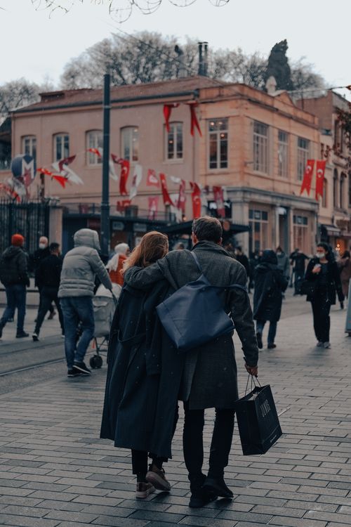Free A couple side hugging as they walk down a busy Istanbul street decorated with Turkish flags. Stock Photo