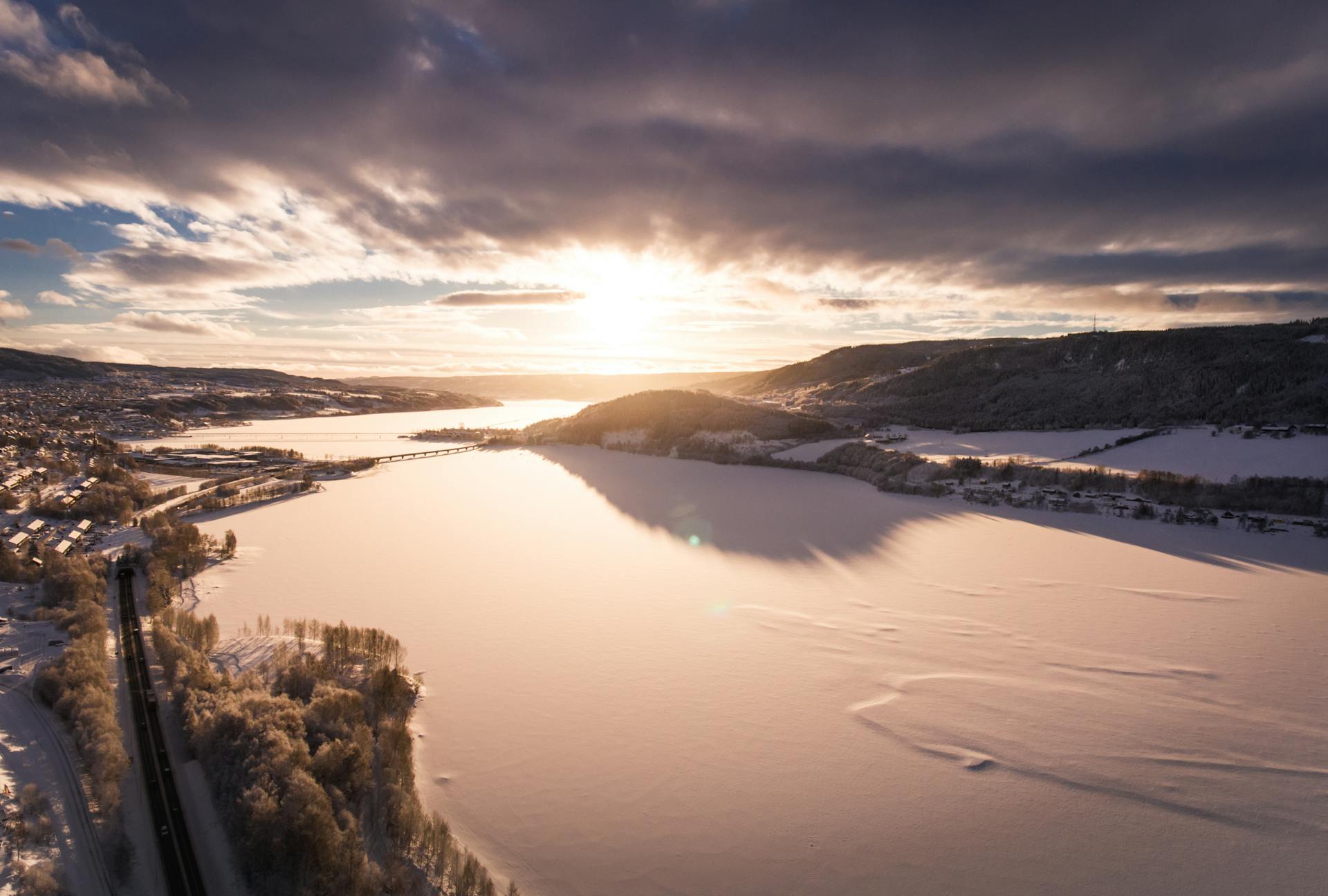 Stunning sunrise view of snowy landscapes in Hol, Norway with frozen lake and mountains.