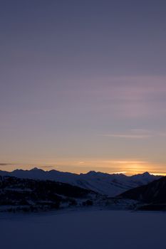 Serene snow-capped mountains under a beautiful evening sky at sunset.