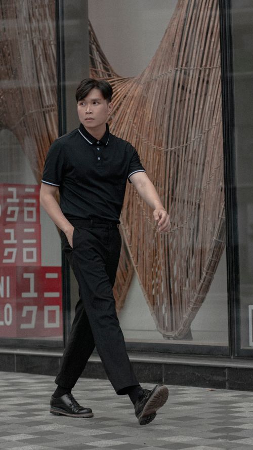 Free Stylish man in black clothes walking confidently on a city sidewalk with modern background. Stock Photo