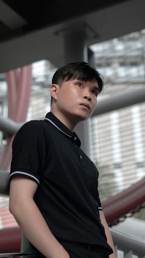Free Portrait of a stylish Asian man in a modern urban background wearing a black polo shirt. Stock Photo