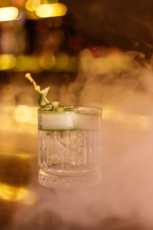 Free A smoke-filled glass of a refreshing cucumber cocktail on a bar counter. Stock Photo