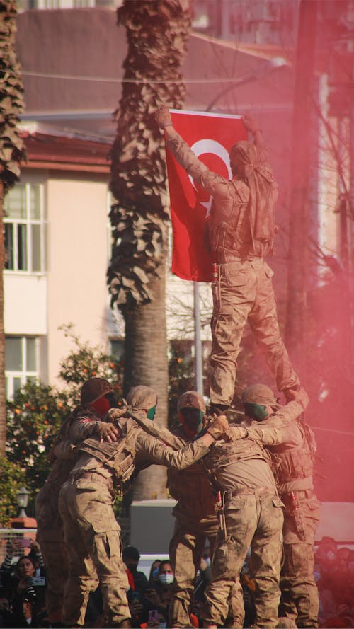 A Man Standing on a Group of People Hanging a Turkish Flag on a Pole