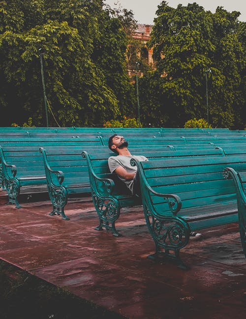 Free Man Sitting and Closing Eyes on Teal Bench Stock Photo