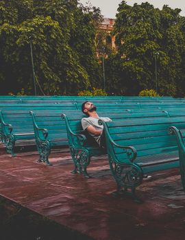 Man Sitting and Closing Eyes on Teal Bench