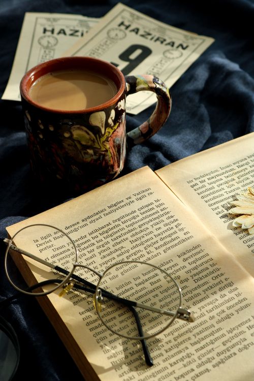 Free Warm setting with coffee, open book, glasses, and calendar for a cozy reading atmosphere. Stock Photo
