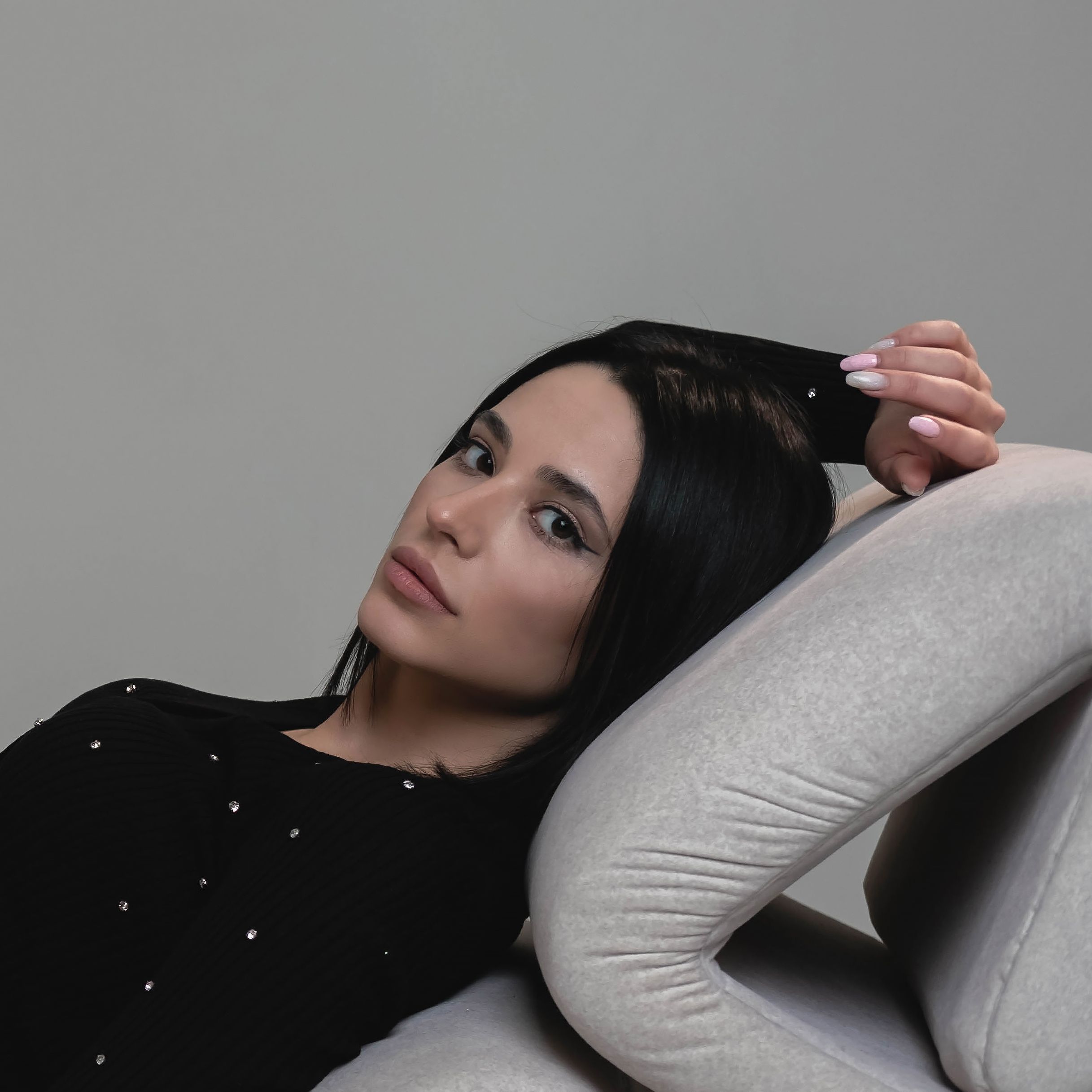 A stylish young woman reclining on a sofa indoors, captured in a serene moment.