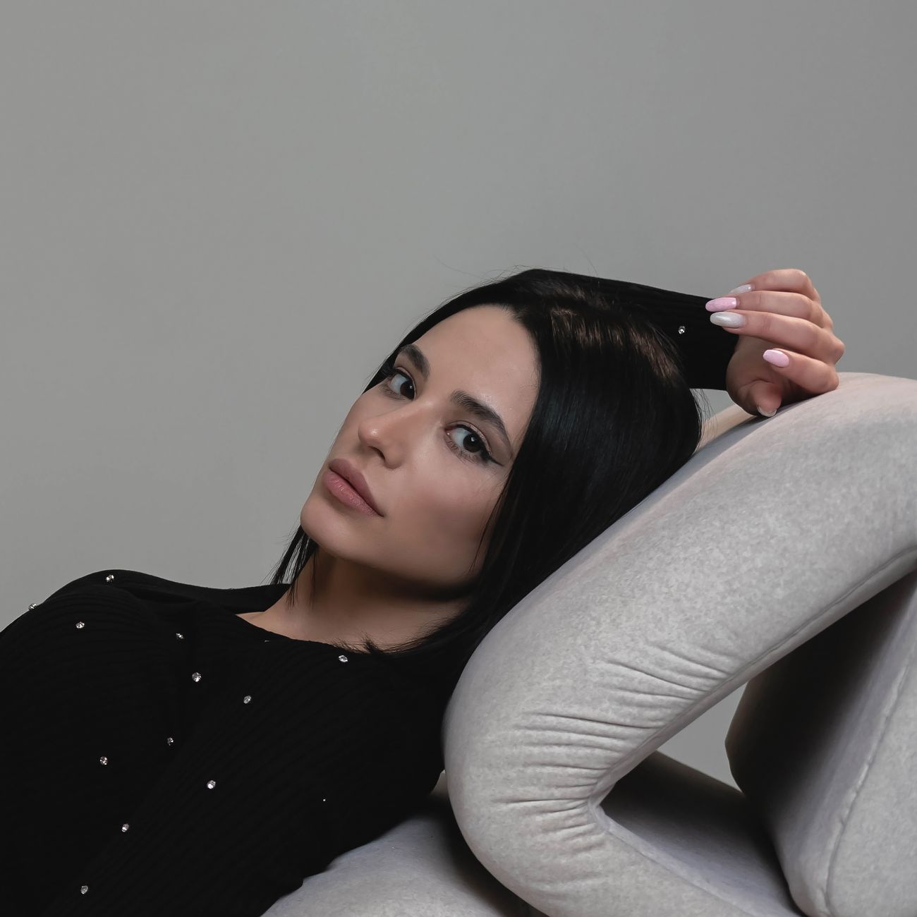 A stylish young woman reclining on a sofa indoors, captured in a serene moment.