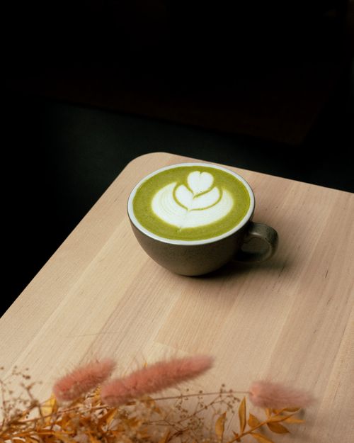 Free A beautifully crafted matcha latte with heart-shaped latte art on a wooden table, perfect for coffee lovers. Stock Photo