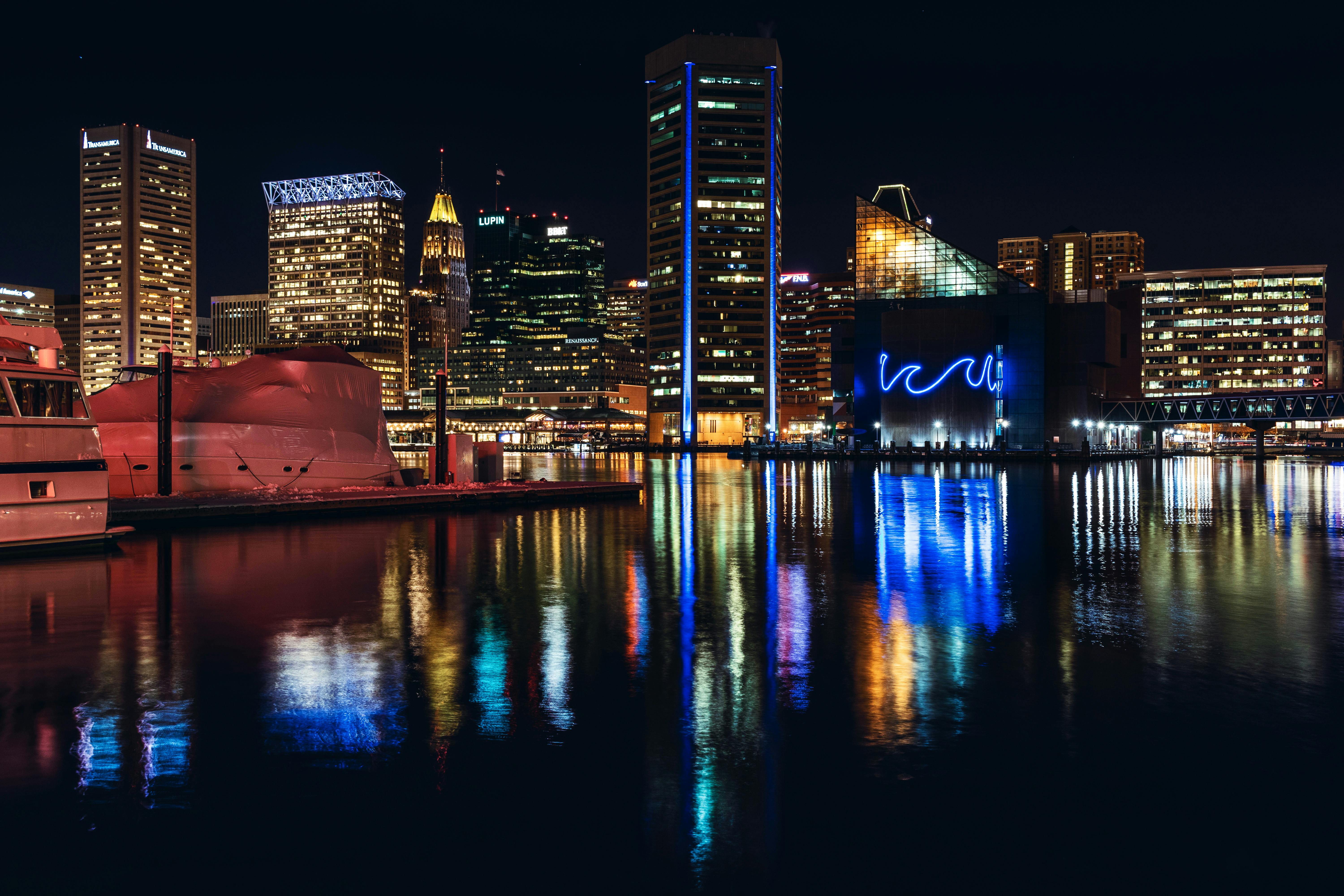 Vibrant Baltimore skyline at night with reflections on Inner Harbor water.