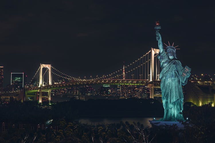 The Odaiba Statue Of Liberty With The Rainbow Bridge On Background In Odaiba, Tokyo, Japan