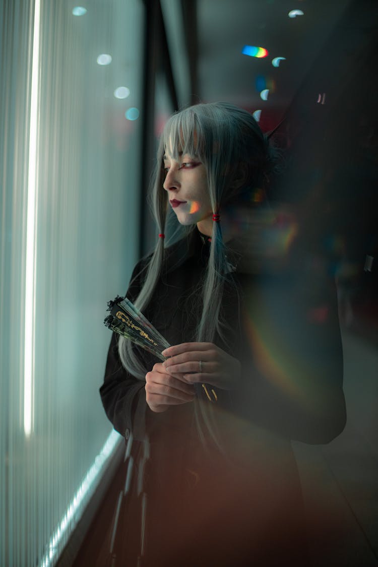 Woman Holding A Japanese Fan And Looking Through Window