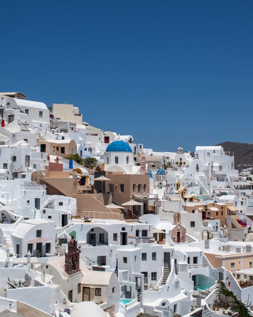 Beautiful daytime view of Fira, Santorini showcasing iconic whitewashed buildings and blue domes.