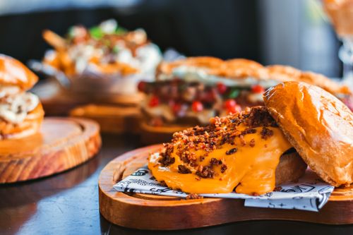 Free Mouth-watering gourmet burgers topped with melted cheese and crispy bits on wooden trays. Stock Photo