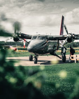 A small aircraft positioned on a tarmac at a rural airfield, ready for takeoff.