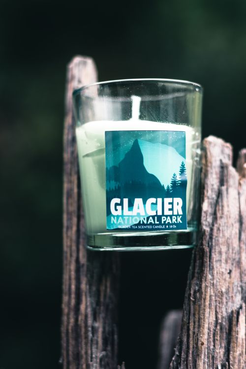 Free Scented candle with Glacier National Park design set against rustic wood outdoors. Stock Photo