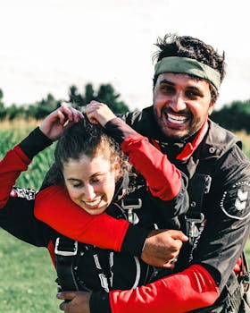 Happy couple in skydiving suits embracing with joy outdoors, capturing the thrill of skydiving.