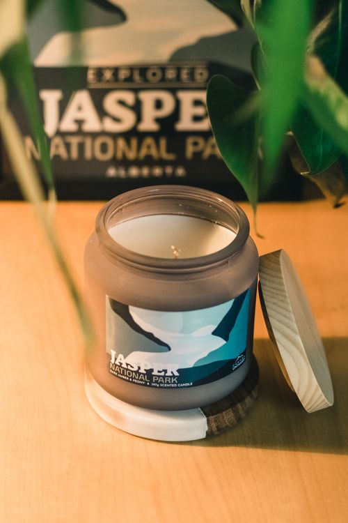 Free Close-up of scented candle featuring Jasper National Park design in warm indoor setting. Stock Photo