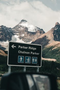 Road sign for Parker Ridge with stunning Canadian Rockies backdrop in summer.