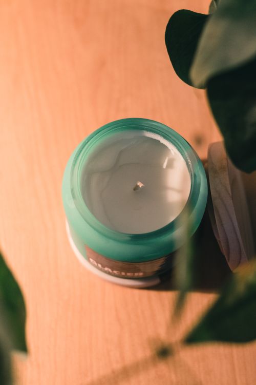 Free Top view of a scented candle in a glass jar surrounded by leaves, creating a soothing still life scene. Stock Photo