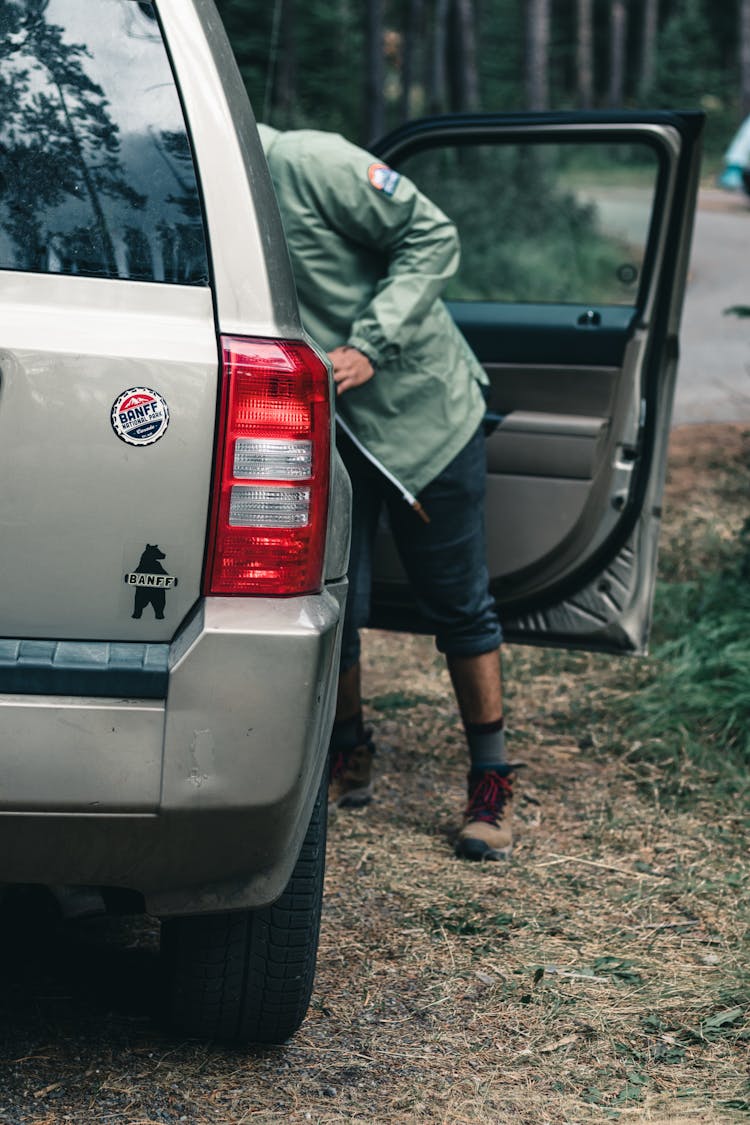 A Man In Green Jacket Getting Things Inside The Car