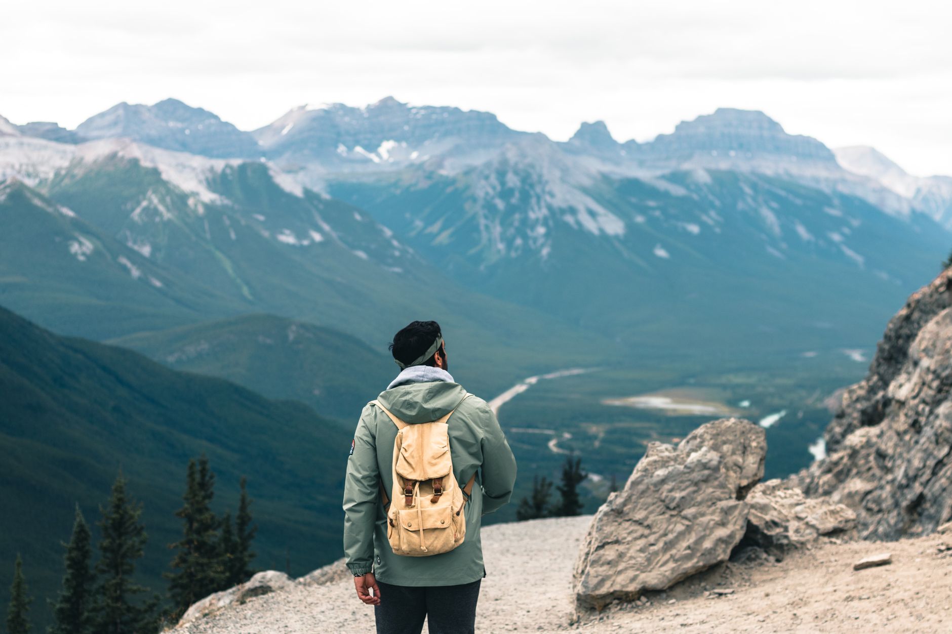 Backpacker overlooking the majestic Canadian Rockies, enjoying a scenic hiking trail.