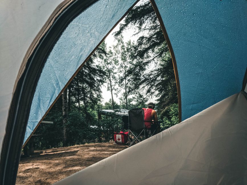 A scenic campground in a Canadian province with an RV parked under trees.