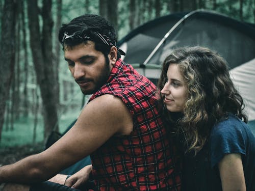 Man in Red and Black Plaid Button Up Shirt Sitting beside Woman in Blue Shirt