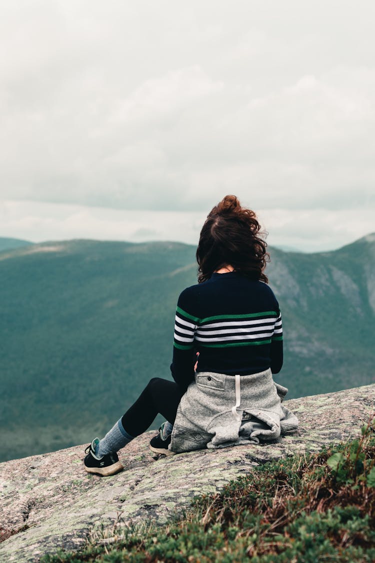 Backview Of Woman Sitting Near A Cliff 