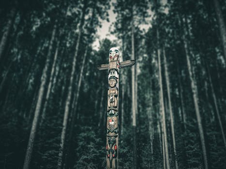 Carved totem pole stands amidst a dense Canadian forest, showcasing traditional indigenous artistry.