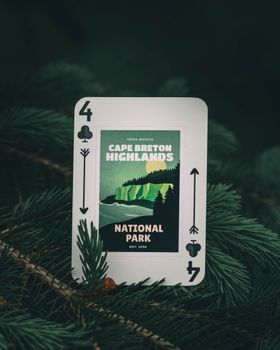 A playing card featuring Cape Breton Highlands amidst forest greenery in Canada.