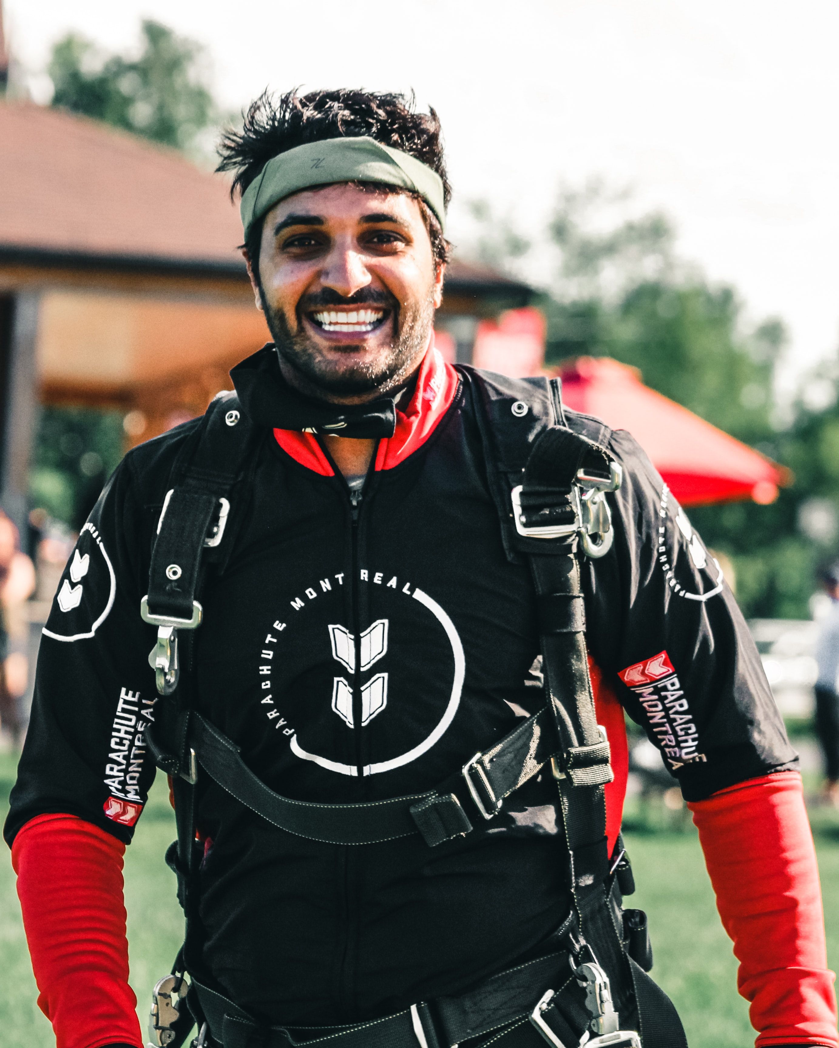 A cheerful man in skydiving gear poses outdoors in Canada, exuding excitement and readiness for the jump.