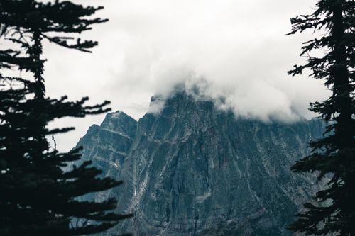 Free Dramatic mist enveloping rugged mountain peaks framed by evergreen trees in Canada. Stock Photo