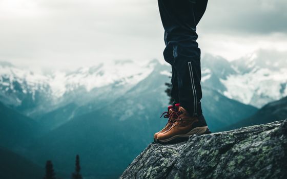 Close-up of hiking boots standing on a rocky cliff in the Canadian mountains during the day.