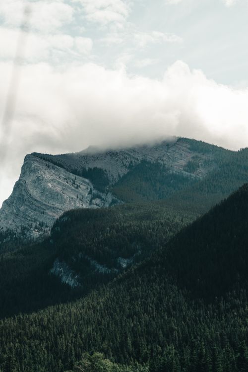 Free A stunning shot of the Canadian Rockies with cloud-draped peaks, showcasing natural beauty. Stock Photo