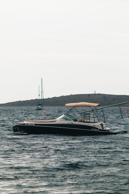 A serene view of a speedboat gliding on a Canadian lake under a bright sky.