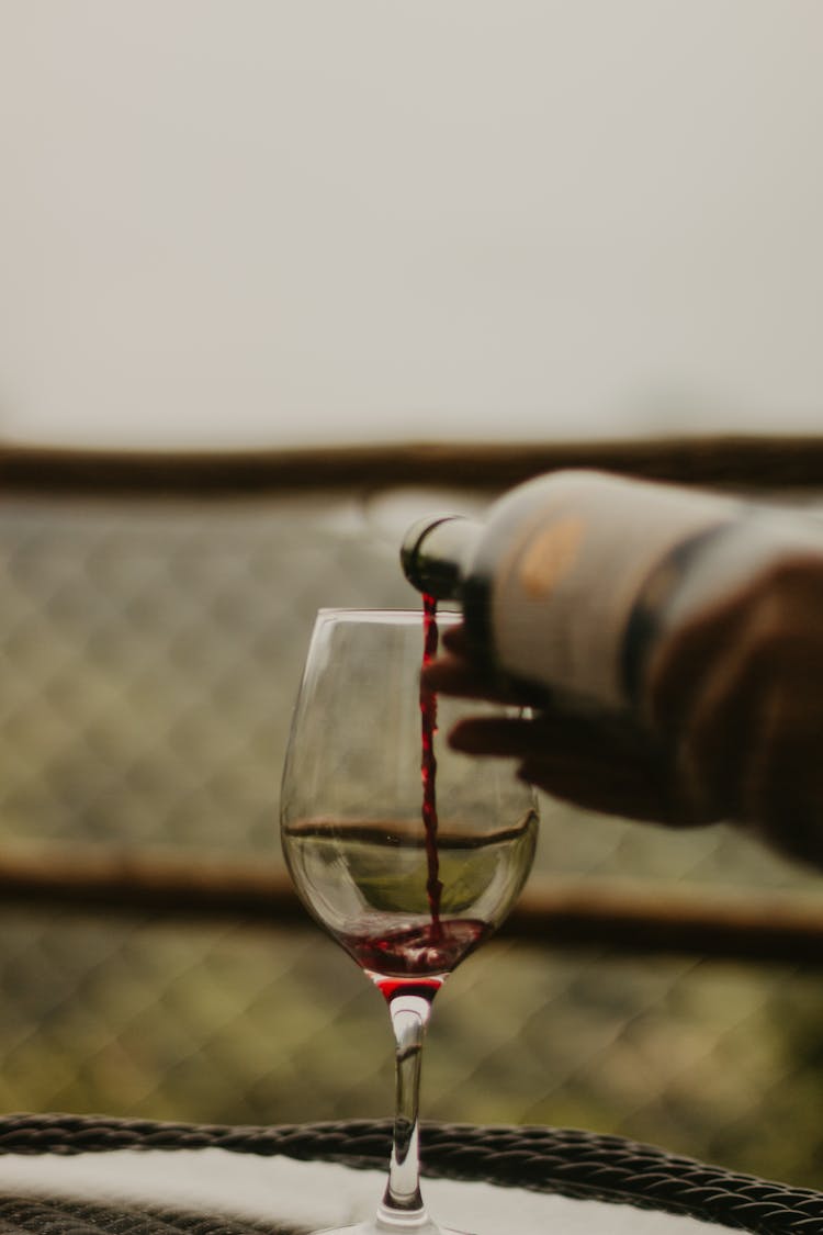 Person Pouring Wine In Glass