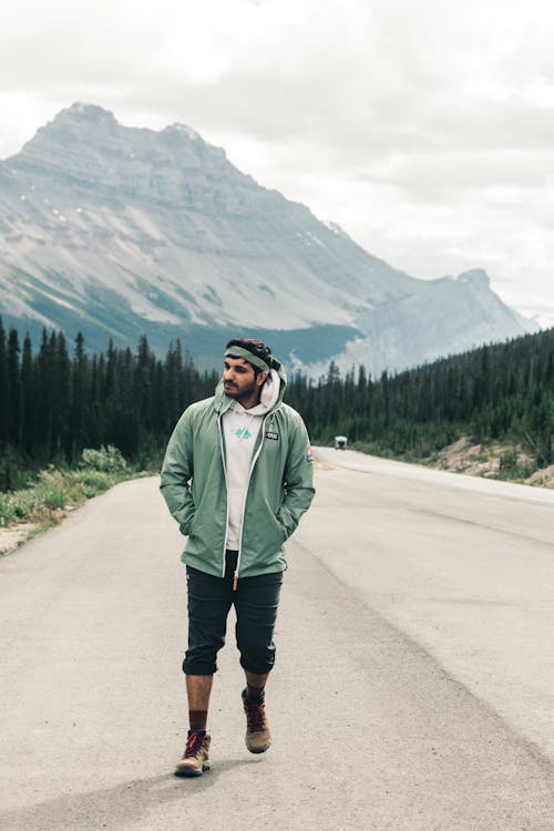 Man in Green Jacket Standing on Road