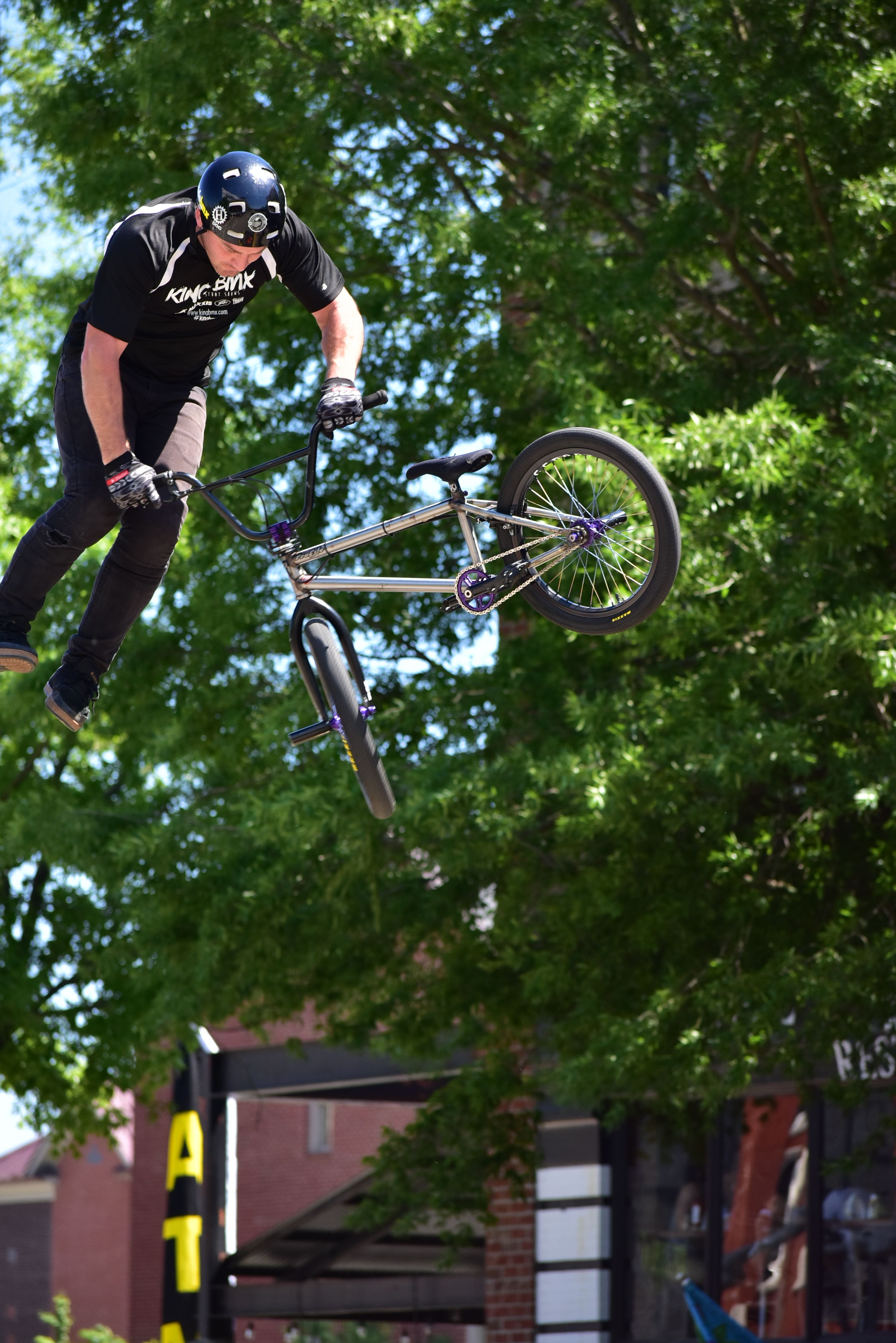BMX biker in mid-air performing a thrilling stunt against a lush green backdrop.