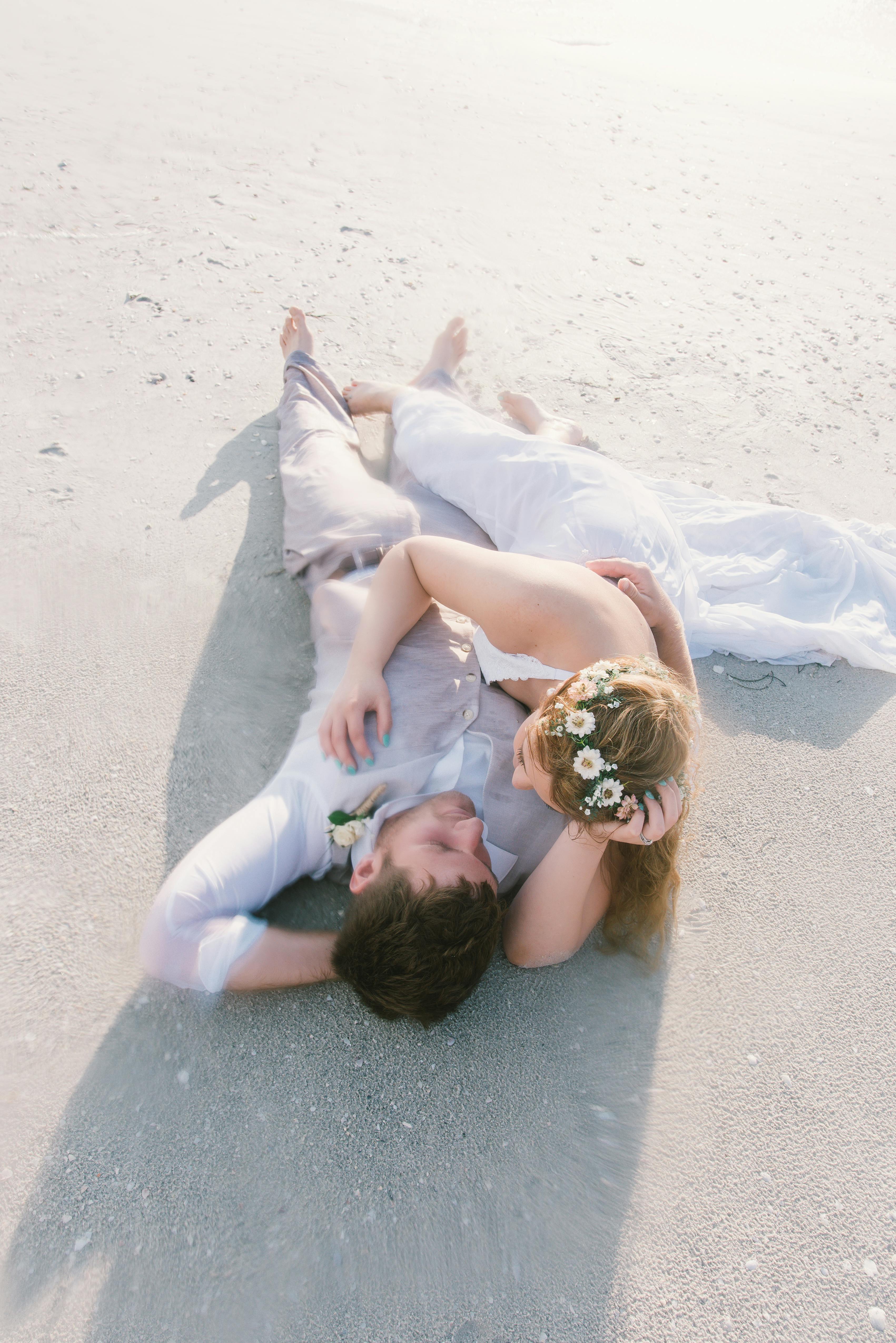 newlywed couple lying on the beach