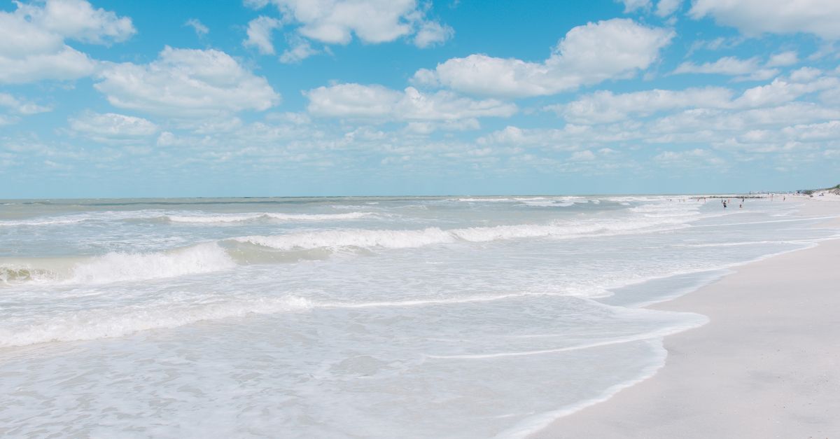Sunny day at St. Pete Beach, Florida with waves crashing on the shoreline under a clear blue sky.