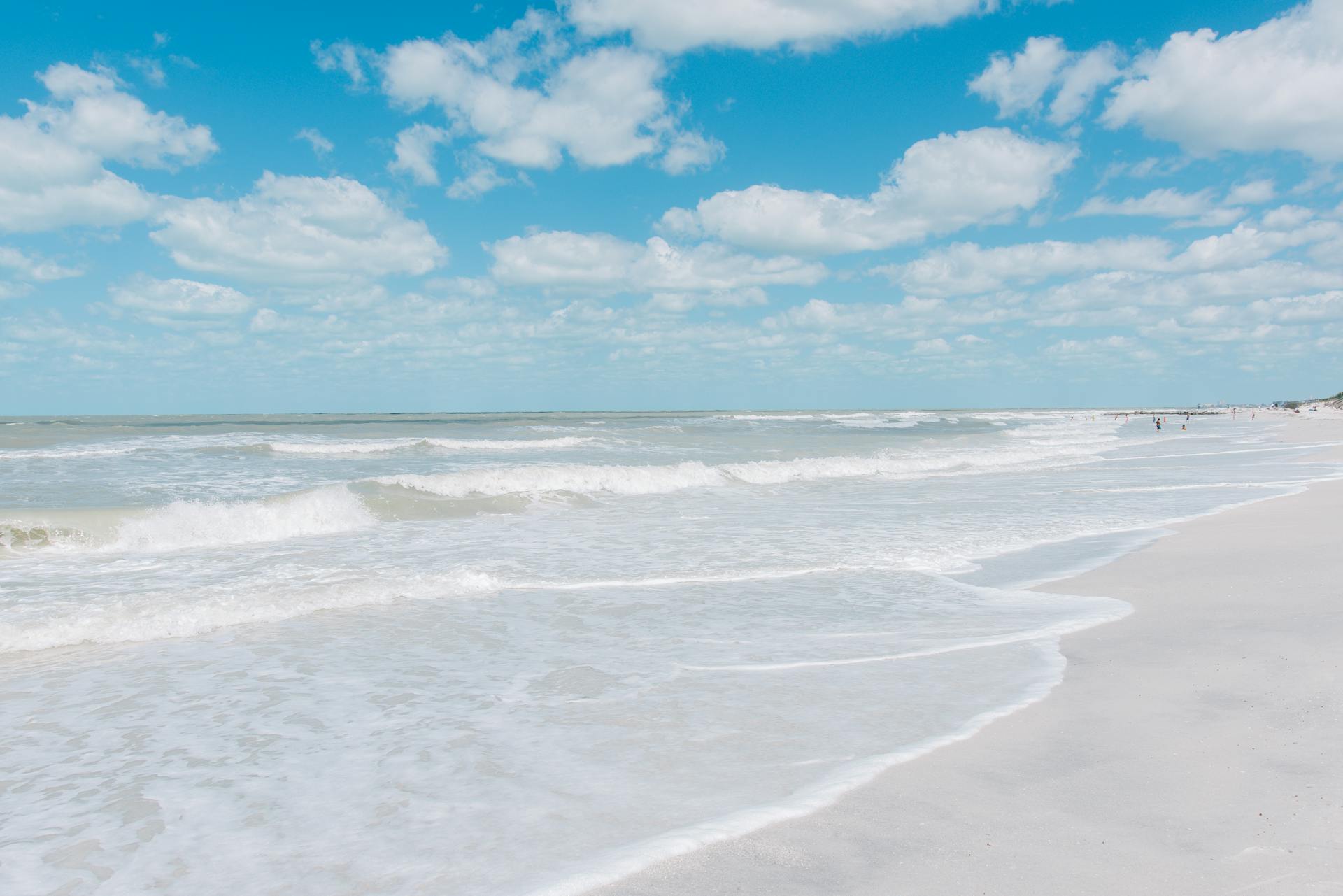 Sunny day at St. Pete Beach, Florida with waves crashing on the shoreline under a clear blue sky.