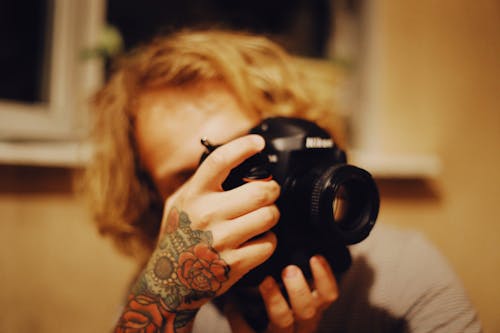 A Person with Rose Tattoo Holding Black  Camera