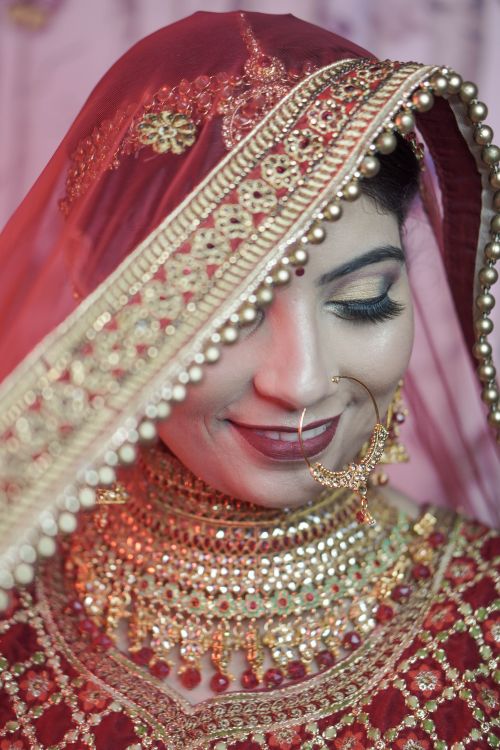 Free Close-up of an Indian bride in ornate red and gold traditional attire showcasing elegance. Stock Photo