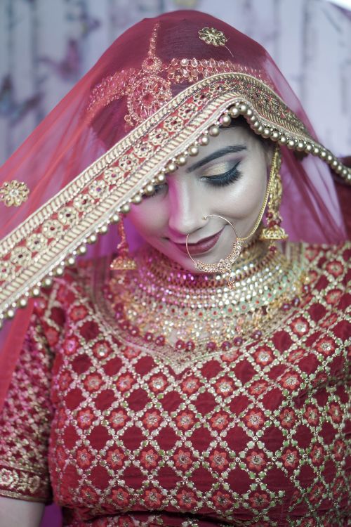 Free Stunning Indian bride in ornate red and gold traditional wear, showcasing cultural elegance. Stock Photo