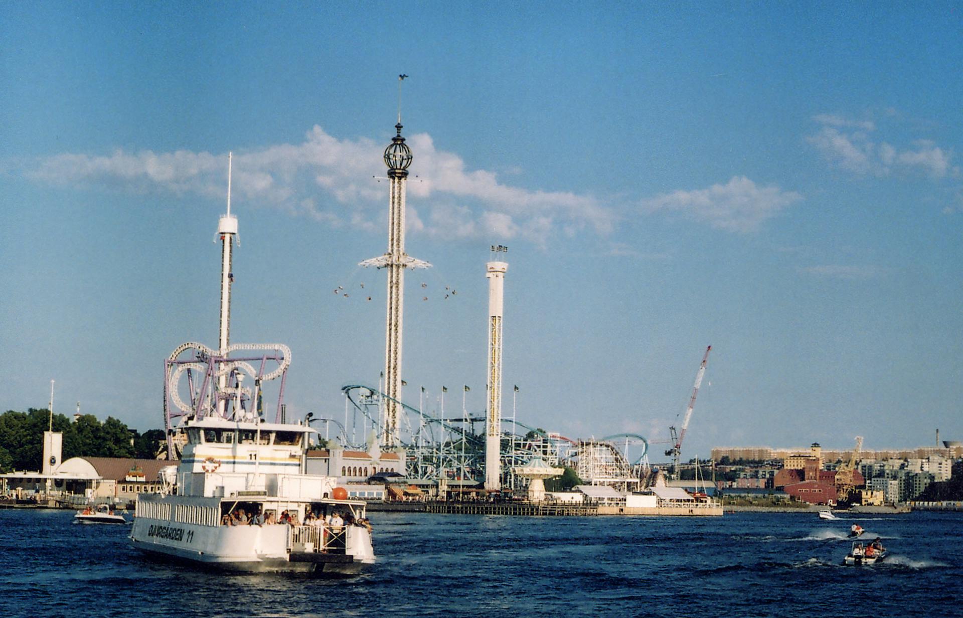 A ferry cruising by a vibrant amusement park in Stockholm, Sweden.