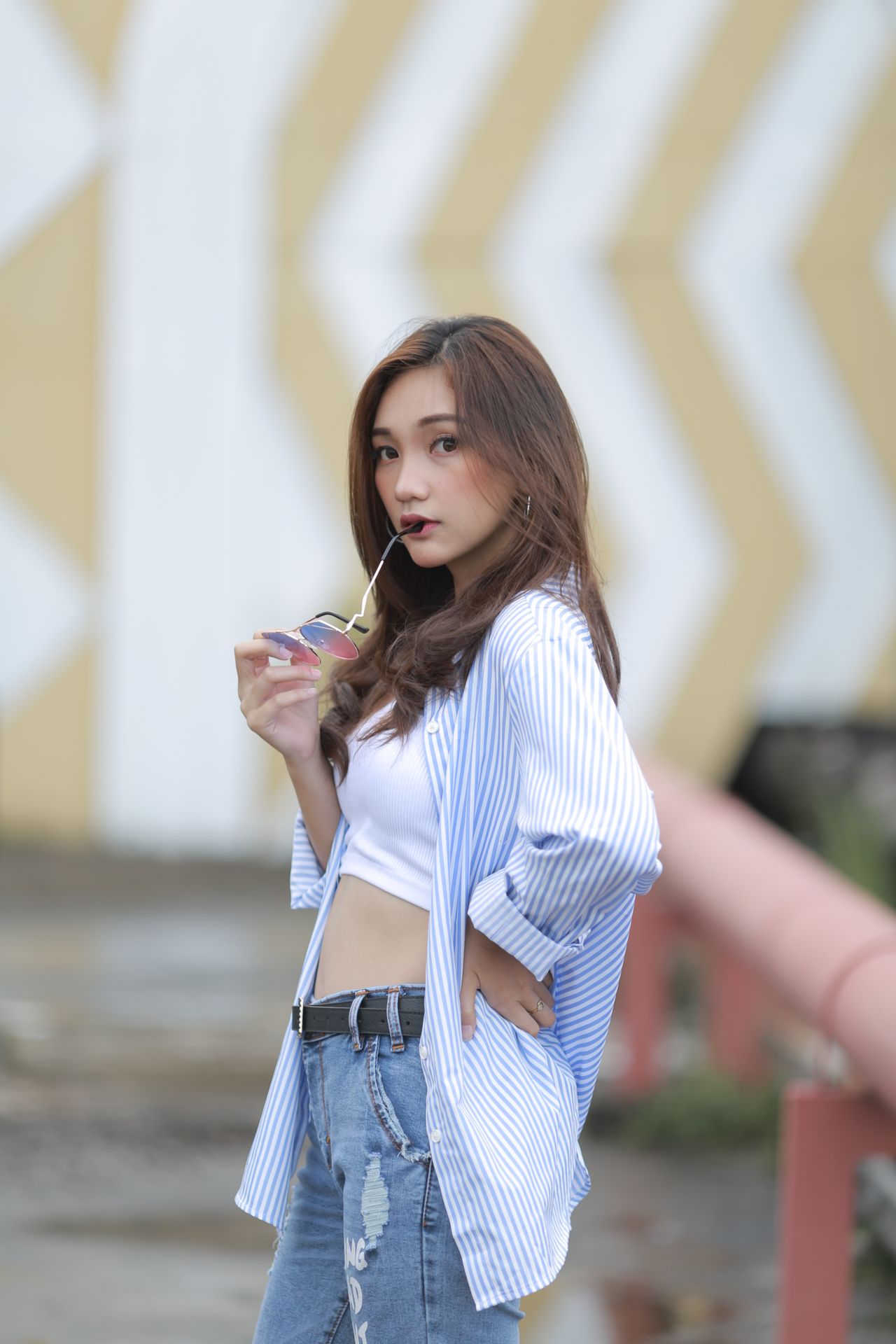 Woman in a striped overshirt, white crop top and jeans